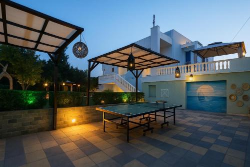 a ping pong table on a patio in front of a house at Villa Small Paradise private pool, jacuzzi, BBQ, complete privacy in Ialyssos