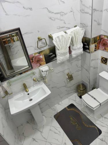 a white bathroom with a sink and a mirror at Art Apart Residence in Tashkent
