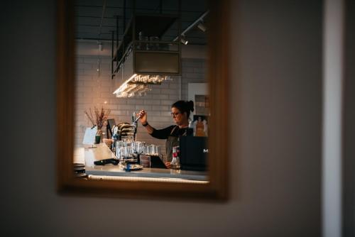 a man standing behind a bar in a mirror at Hotell & Bistro Rödesund in Karlsborg