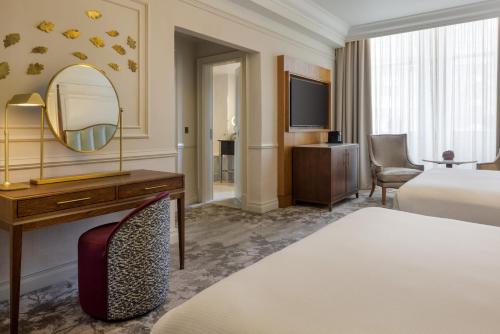 a hotel room with a bed and a mirror at The Caledonian Edinburgh, Curio Collection by Hilton in Edinburgh