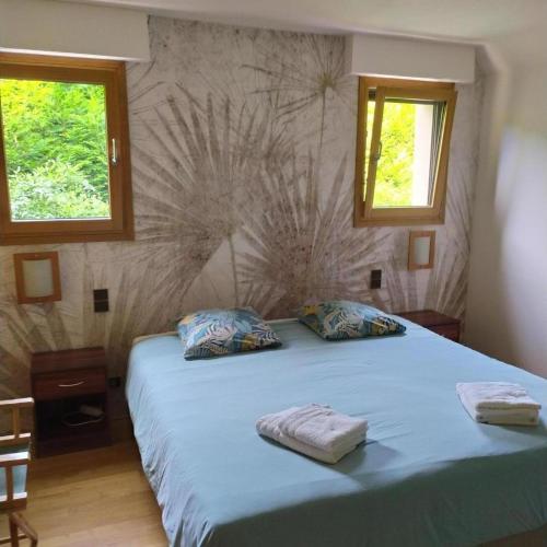 - une chambre avec un lit doté de draps bleus et 2 fenêtres dans l'établissement Thy lou, à Baden