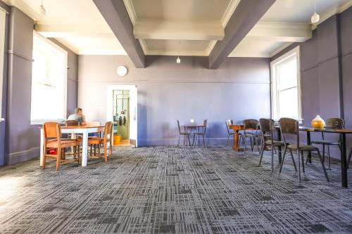 a room with tables and chairs and a person sitting at a table at Crashpalace Napier in Napier