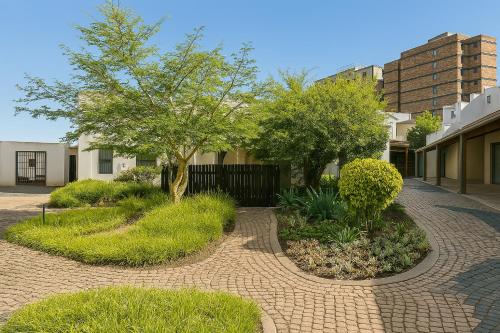 een bakstenen pad met bomen en planten in een binnenplaats bij Charming apartment With Private Balcony in Johannesburg