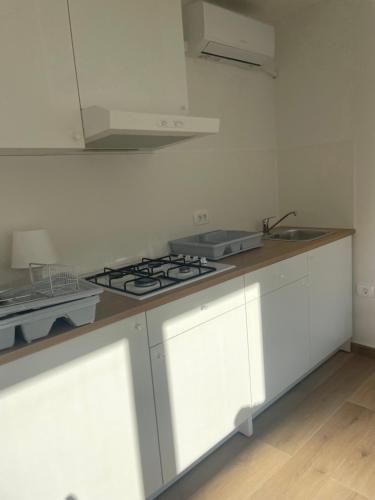 a kitchen with white cabinets and a stove top oven at Apartma Škorenjček in Prestranek