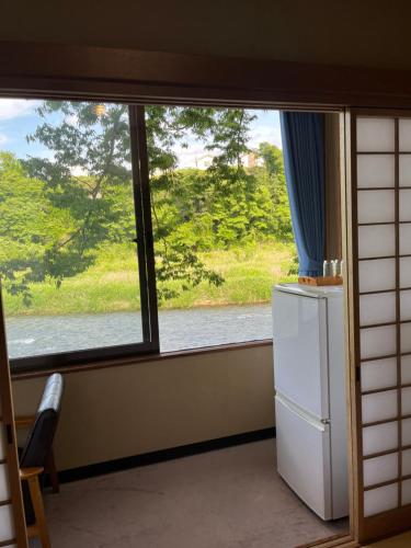 a window in a room with a refrigerator and a view at 料理自慢の温泉宿せせらぎ荘 in Chichibu
