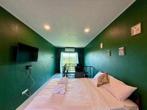 a bedroom with a bed with a green wall at Hacienda Resort - Mae Phim in Mae Pim