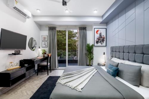 a bedroom with a bed and a desk and a television at BedChambers Serviced Apartments, MG ROAD in Gurgaon