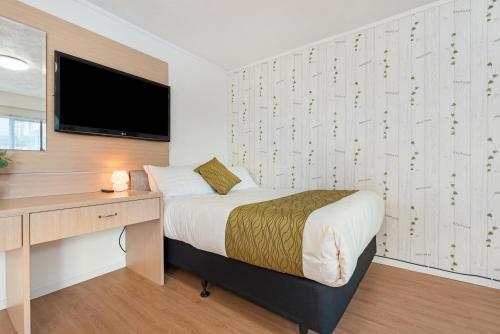 a bedroom with a bed and a desk and a television at Travel Air Motel in Auckland