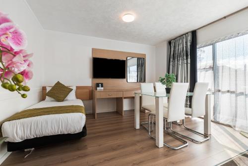 a bedroom with a bed and a desk and a table at Travel Air Motel in Auckland