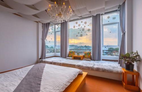 a bedroom with a bed and large windows with a chandelier at Phố Thường Garden in Da Lat