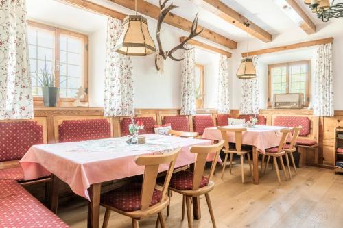 a dining room with tables and chairs and windows at Ferienwohnungen Windischlehen am Zeller See in Maishofen