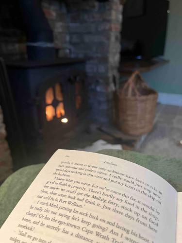 an open book sitting on a table with a fireplace at Fern Cottage Iden, Rye in Iden