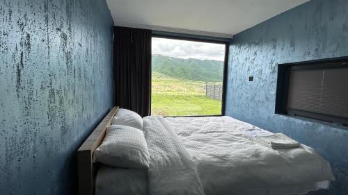 a bedroom with a bed and a large window at Shahdag Berghoff House in Qusar