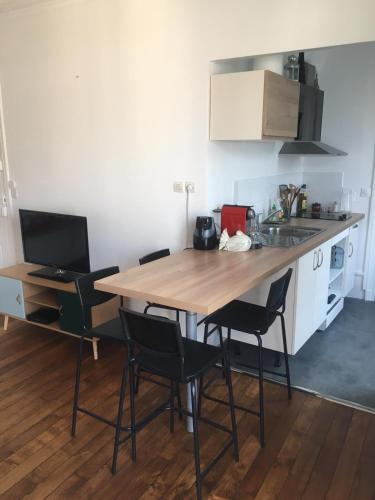 une cuisine avec une table en bois et des chaises noires dans l'établissement T2 plein centre-ville, Gare à 5 min, Près Ermitage, à Maisons-Laffitte