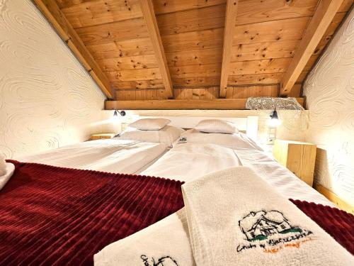 a large bed in a room with wooden ceilings at Chata w Bieszczadzie apartamenty i domki z basenem Bieszczady in Polańczyk
