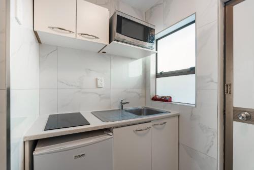 a kitchen with a sink and a microwave at Travel Air Motel in Auckland