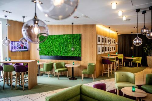 a restaurant with tables and chairs and a green wall at Scandic Aalborg City in Aalborg