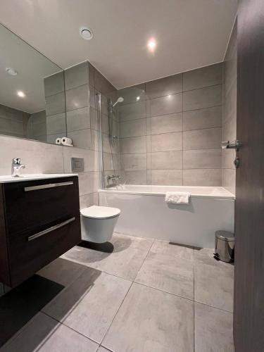 a bathroom with a tub and a toilet and a sink at Cosy Studio with private entrance & Parking in Bracknell