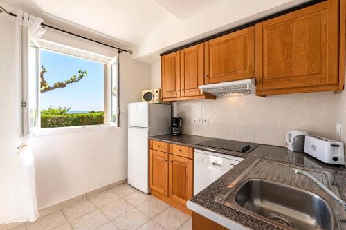 une cuisine avec un évier et une fenêtre dans l'établissement Prunete - Piscine - Vue mer, à Cervione