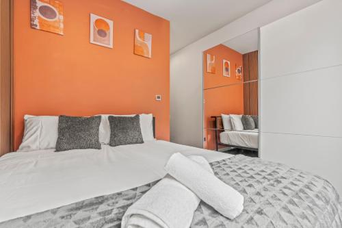 une chambre avec un lit blanc avec un mur orange dans l'établissement Iron Haven - Central B'ham - Luxury Apt, à Birmingham