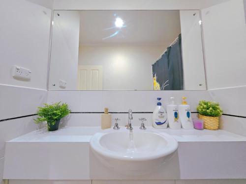 a white bathroom with a sink and a mirror at Eden - Love of Wright 伊甸园 - 怀特之爱 in Adelaide