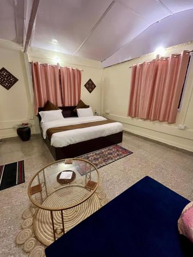 a hotel room with two beds and a glass table at EcoEscape Mukteshwar in Mukteswar