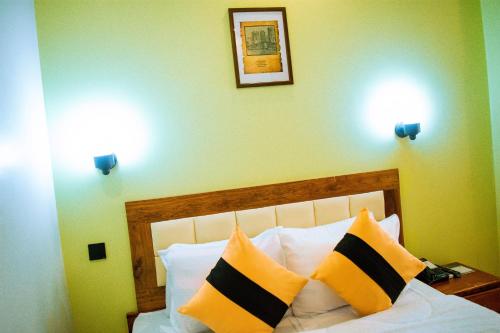 a bedroom with a bed with yellow and black pillows at MARK-A GARDEN HOTEL Kawe in Dar es Salaam