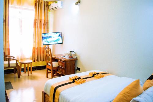 a bedroom with a bed and a table and a desk at MARK-A GARDEN HOTEL Kawe in Dar es Salaam
