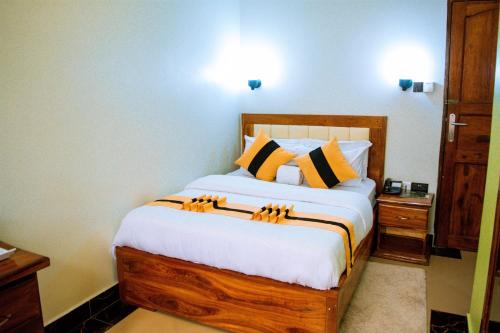 a bedroom with a bed with yellow and black pillows at MARK-A GARDEN HOTEL Kawe in Dar es Salaam
