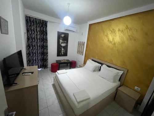 Un dormitorio con una cama blanca y un televisor. en Hotel Fabio, en Tirana