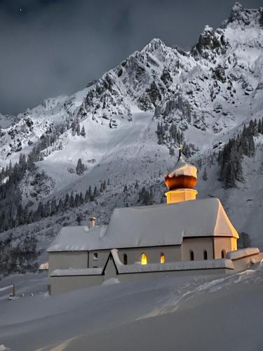a building in front of a snow covered mountain at Arlberg Motel Ski-In & Ski-Out access to Austrias largest ski area in Stuben am Arlberg