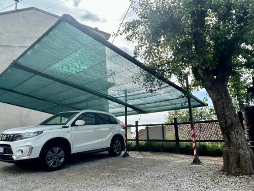 a white car parked under a canopy next to a tree at Takápradalù in Cisterna dʼAsti
