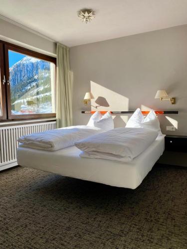 a bedroom with a large bed with a large window at Arlberg Motel Ski-In & Ski-Out access to Austrias largest ski area in Stuben am Arlberg