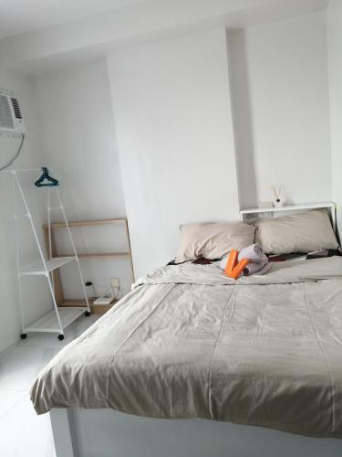 a white bedroom with a bed with an orange object on it at Casa Mira Guadalupe Harmony Home Cebu City in Cebu City