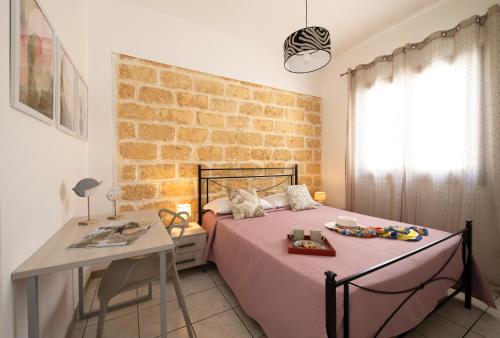 een slaapkamer met een bed en een tafel en een bakstenen muur bij Villa Lilibeth in San Vito lo Capo
