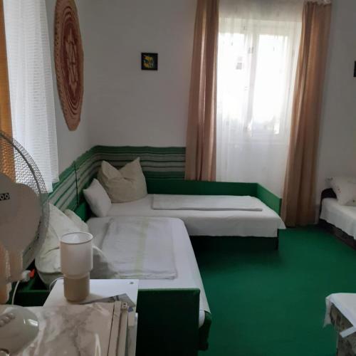 a room with two beds and a green floor at Faragó Vendégház in Abádszalók