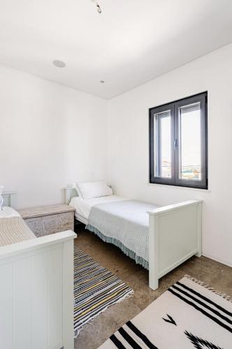 a white bedroom with a bed and a window at Bica Vista in Lourinhã