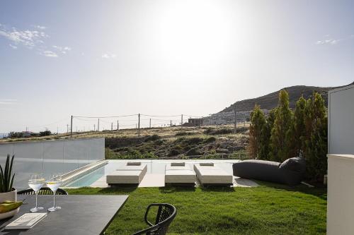 a patio with a table and chairs and a pool at Dea Luna Villas, Heated Pool & 5star Resort Access, By ThinkVilla in Panormos Rethymno