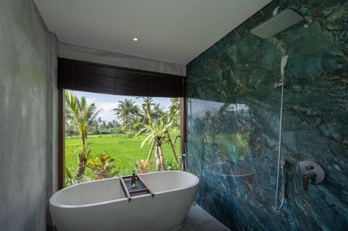 a bathroom with a tub and a large window at Emana Akatara in Ubud