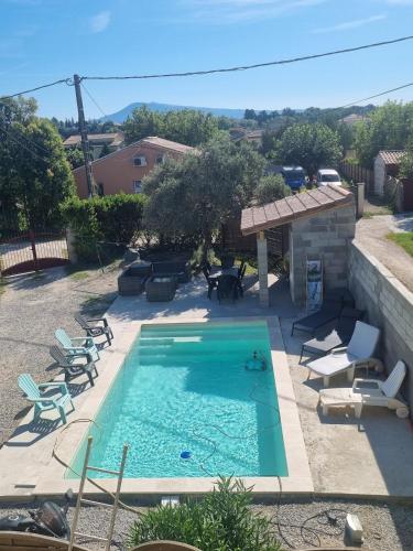 - une piscine avec des chaises longues et des chaises dans la cour dans l'établissement Appartement au calme, à Sarrians