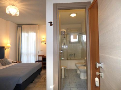 a bedroom with a bed and a bathroom with a shower at Hotel Giulio Cesare in Cinquale