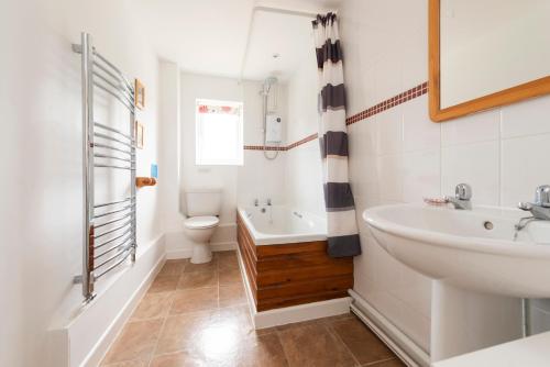 a bathroom with a sink and a tub and a toilet at Buckingham Cottage - Lancombes House in Powerstock
