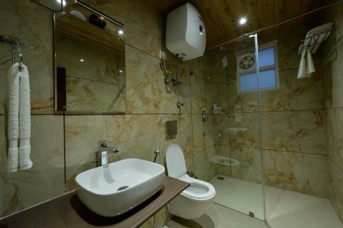 a bathroom with a sink and a toilet and a shower at Rajgriha Luxury Kasauli Stay in Kasauli