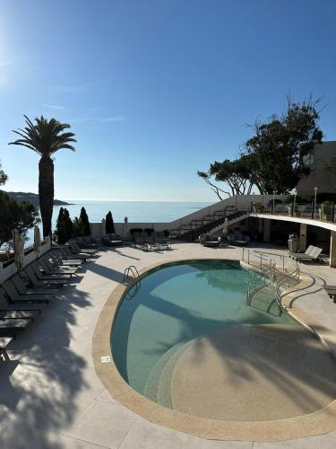 a large swimming pool with chairs and a palm tree at Ilunion Caleta Park in Sant Feliu de Guixols