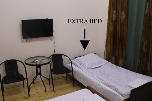 a room with a bed and two chairs and a table at Guesthouse LUKA in Kutaisi