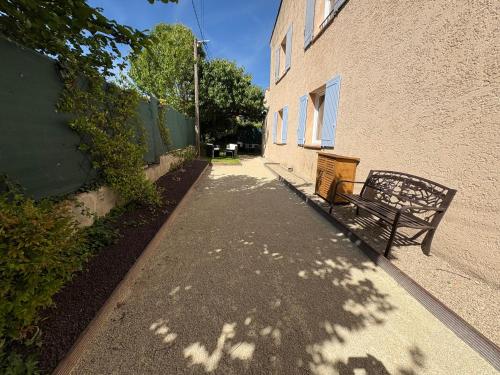 un banco sentado en una acera junto a un edificio en Logement avec jardin et terrain de pétanque privé, en Venelles