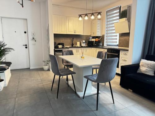 a kitchen and living room with a white table and chairs at Modern Apartment in Dumbrăviţa