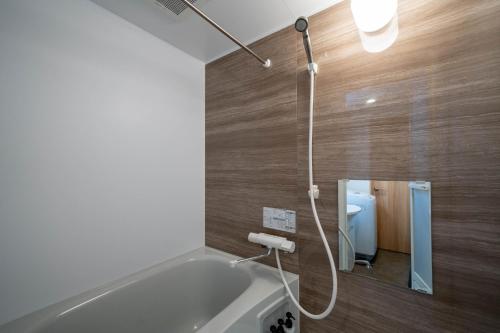a bathroom with a tub with a shower and a toilet at LudiCent717 - Vacation STAY 08156v in Toyohira