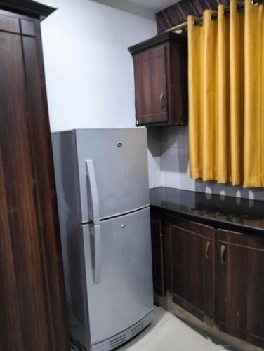 een keuken met een roestvrijstalen koelkast en houten kasten bij Sohail arcade in Islamabad