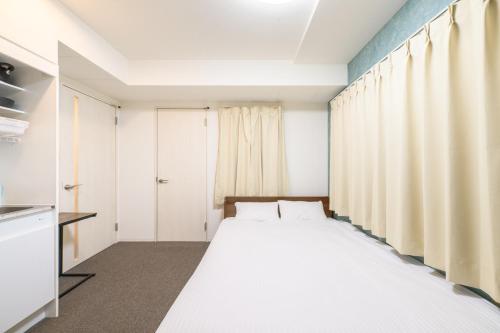 a bedroom with a large white bed and curtains at LudiCent717 - Vacation STAY 08159v in Toyohira